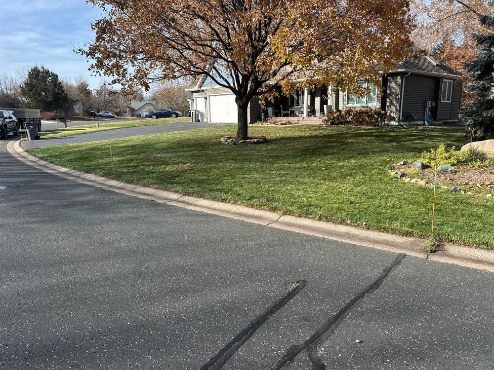 Residential property with a house, tree, and landscaped yard on a suburban street.