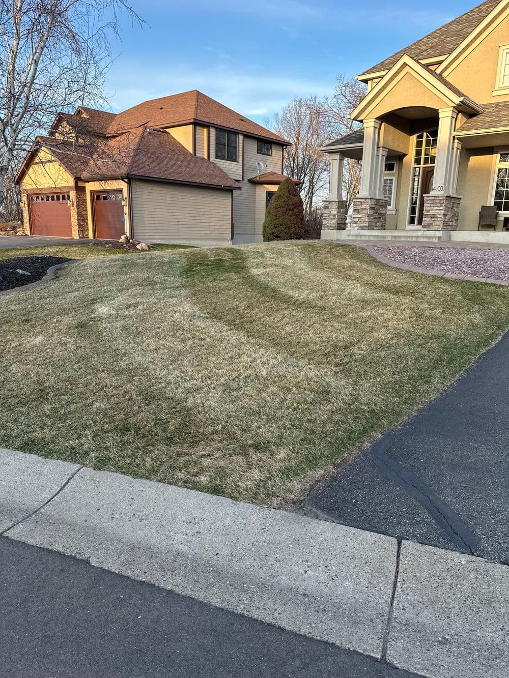 Front yard with green grass and landscaped home exterior, suburban neighborhood setting.