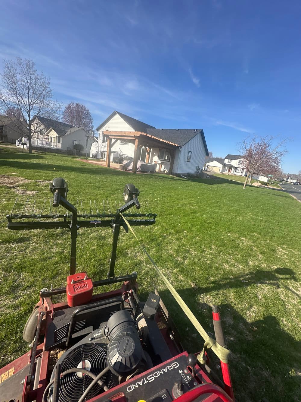 Lawn care equipment in foreground with a residential home and clear blue sky in background.