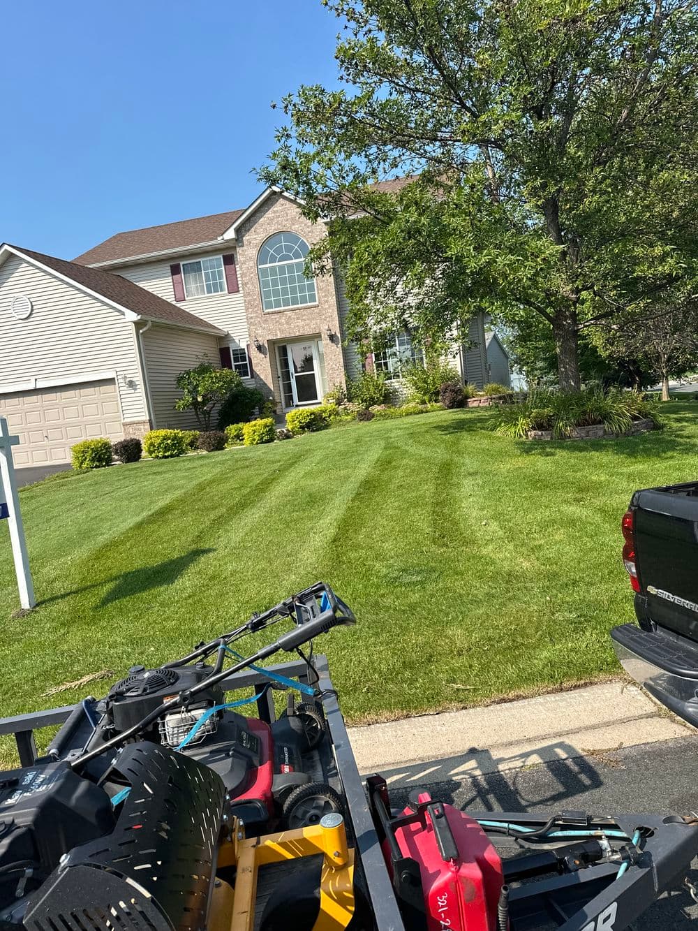 Well-maintained green lawn with striped patterns in front of a house on a sunny day.