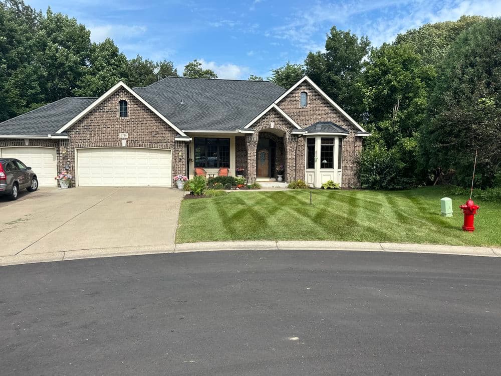 Brick house with a landscaped yard and a fire hydrant, located on a quiet suburban street.