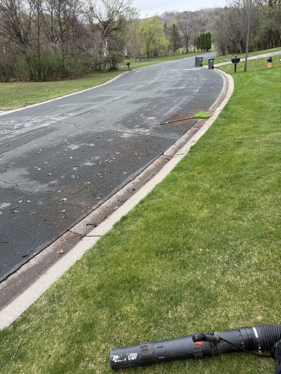 A spring cleanup in progress — curb line blown clean, blower in hand