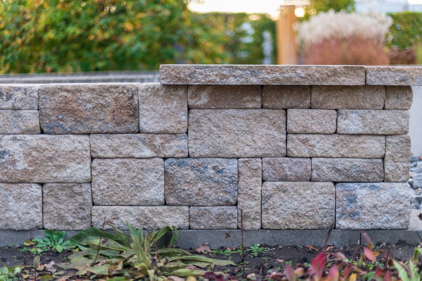 A segmental block retaining wall edging a planted bed