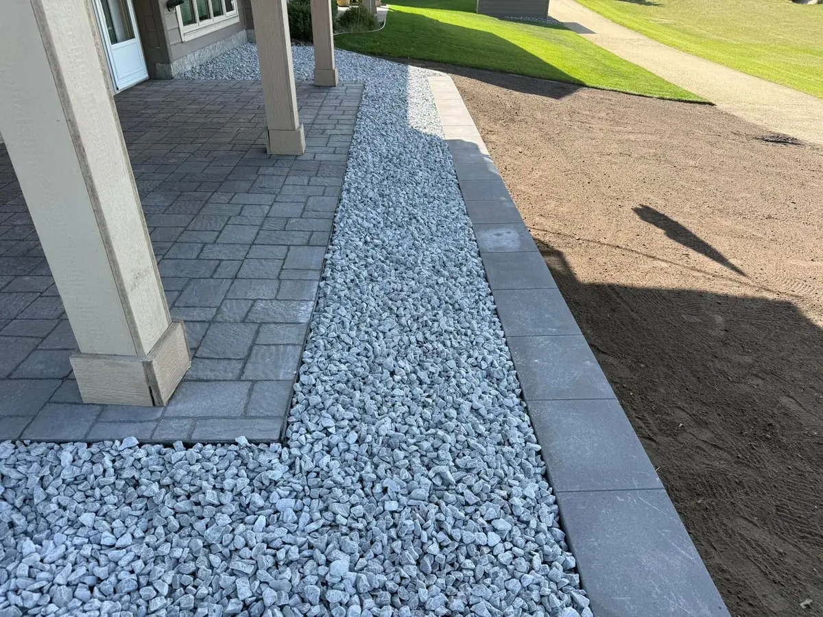 A paver walk edged with river rock beside a fresh lawn — our own work