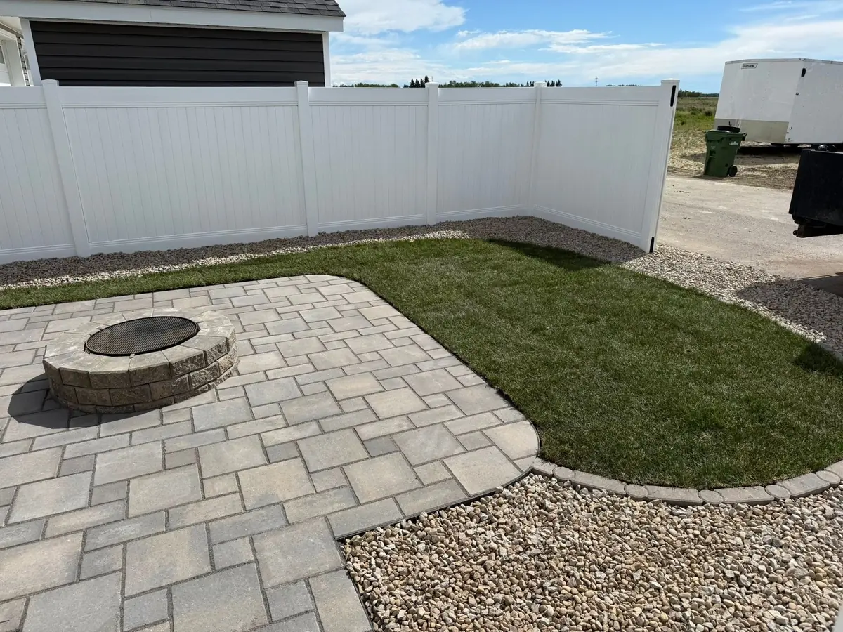 Fresh sod and a new paver patio along a white fence — our own work